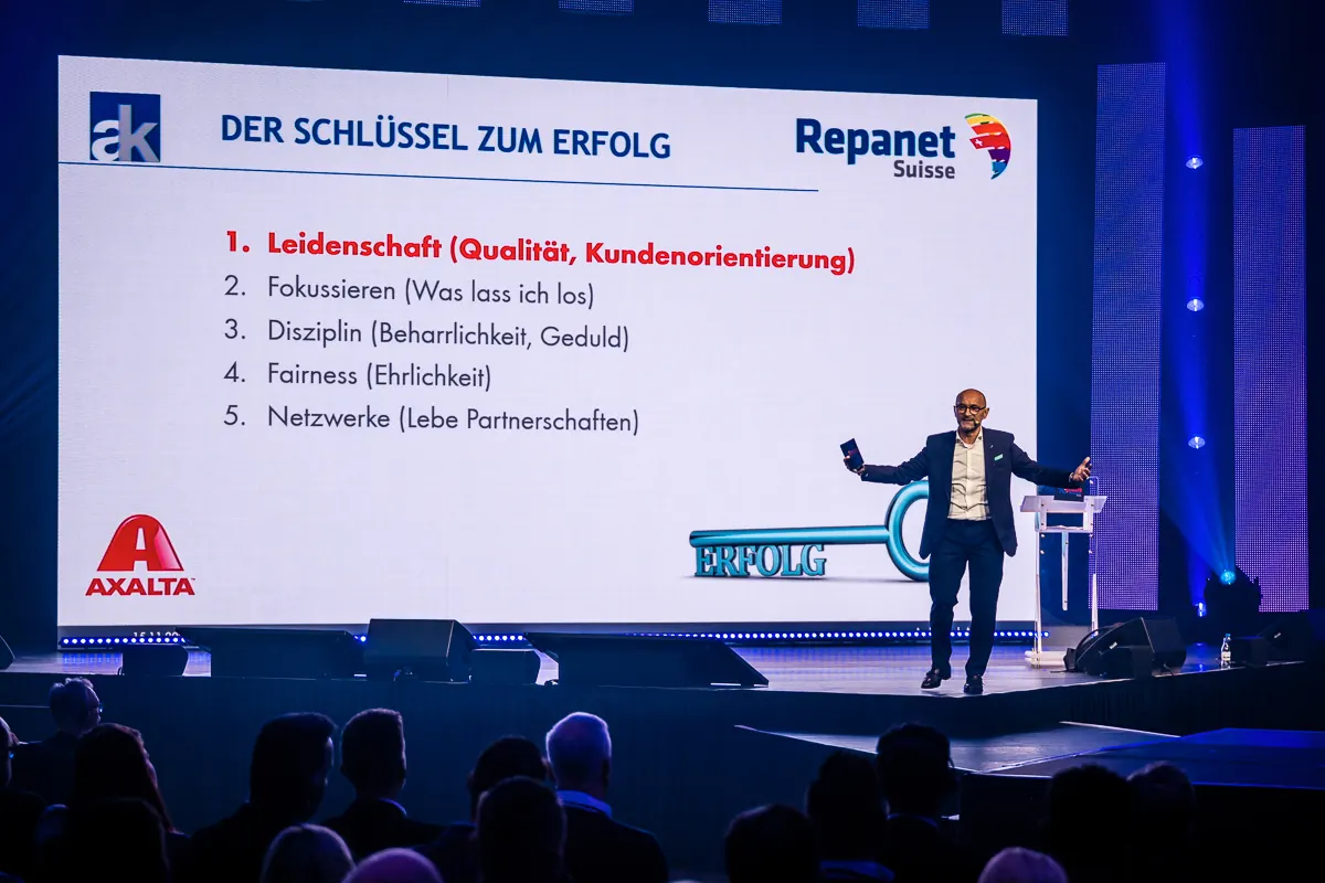 Enzo Santarsiero auf der Bühne vor einer Folie „Der Schlüssel zum Erfolg“ mit fünf Punkten