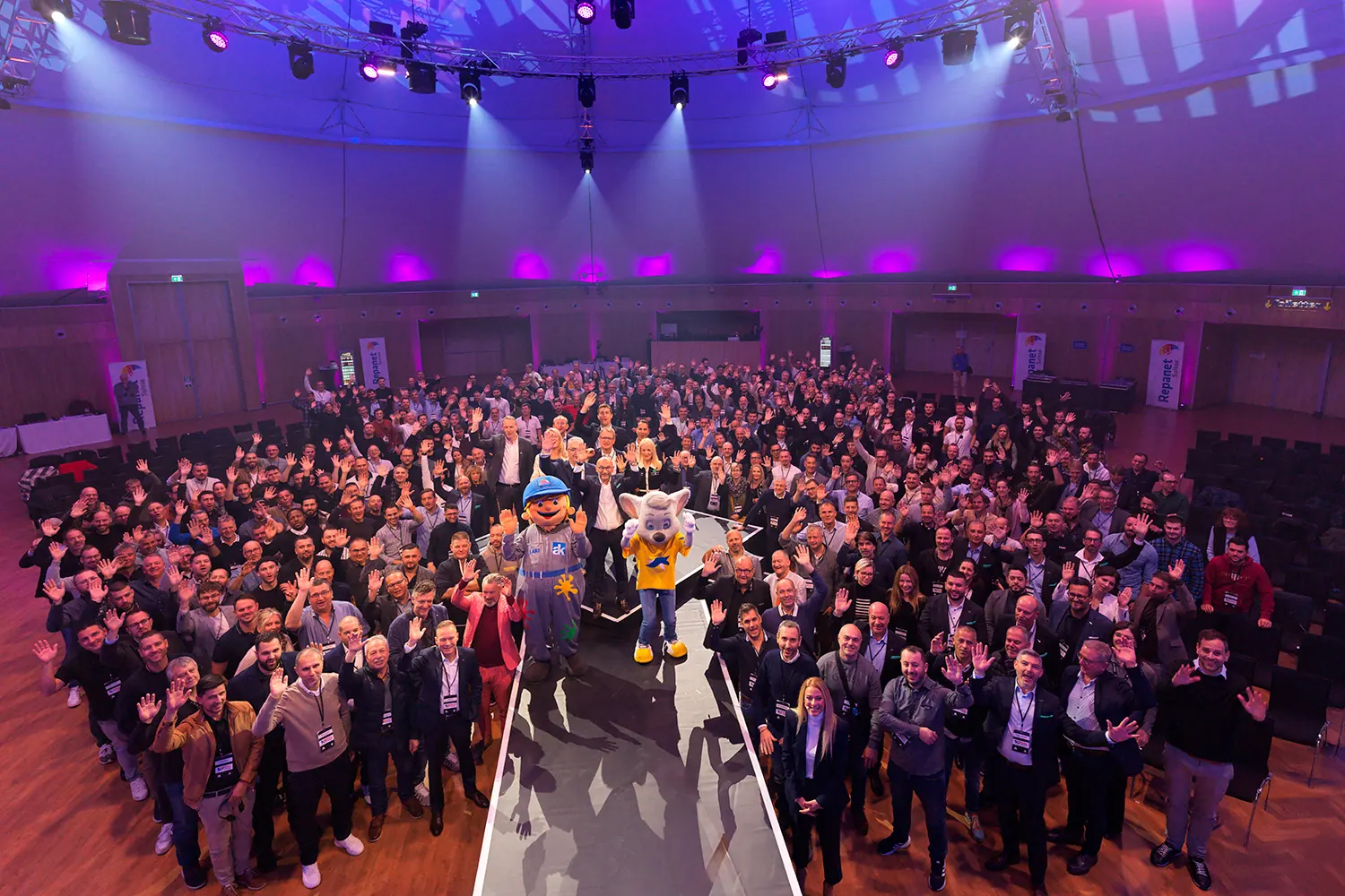 Gruppenbild der Teilnehmenden in einer grossen, violett beleuchteten Halle