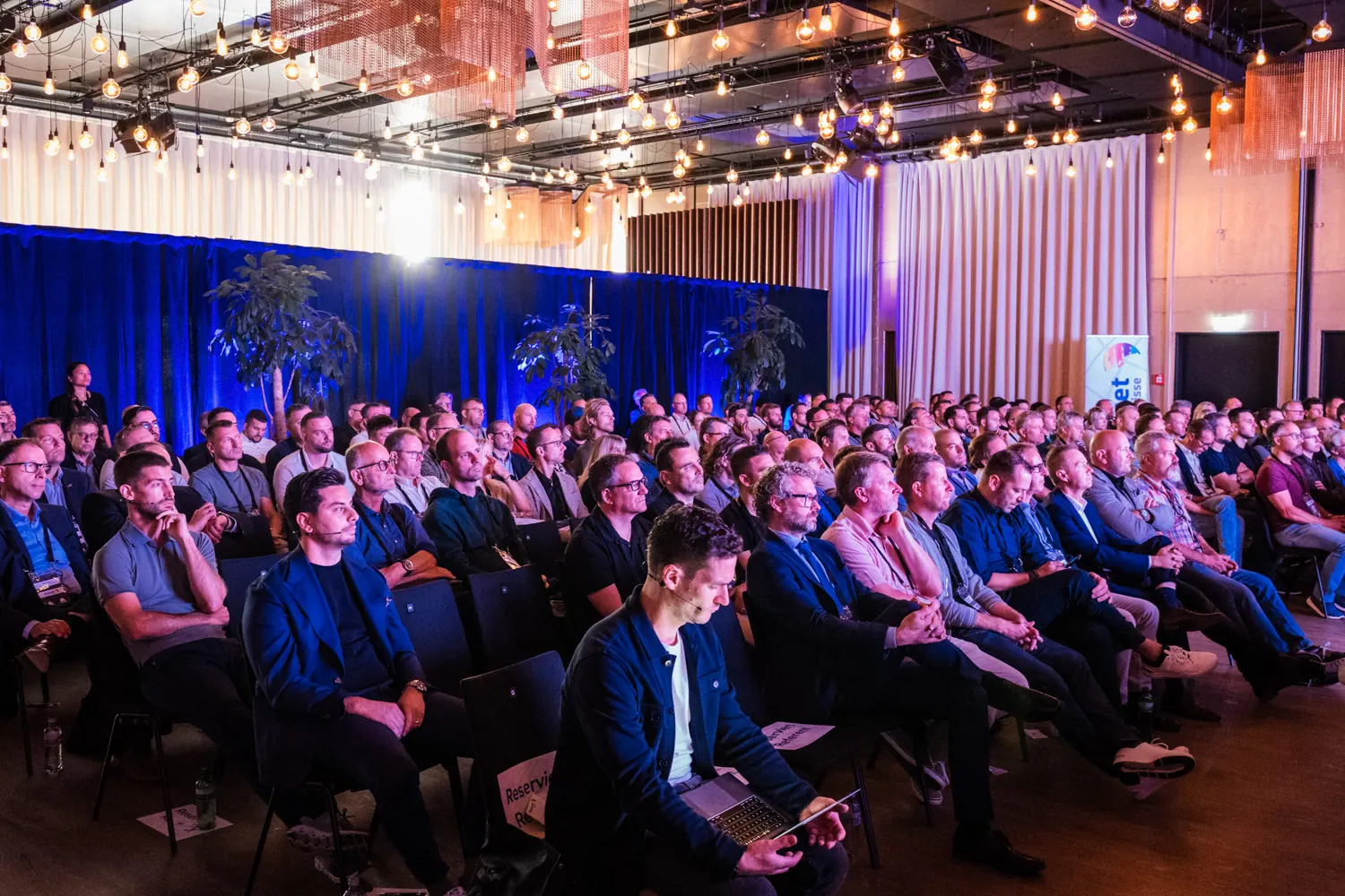 Voll besetzter Saal, das Publikum verfolgt aufmerksam einen Vortrag
